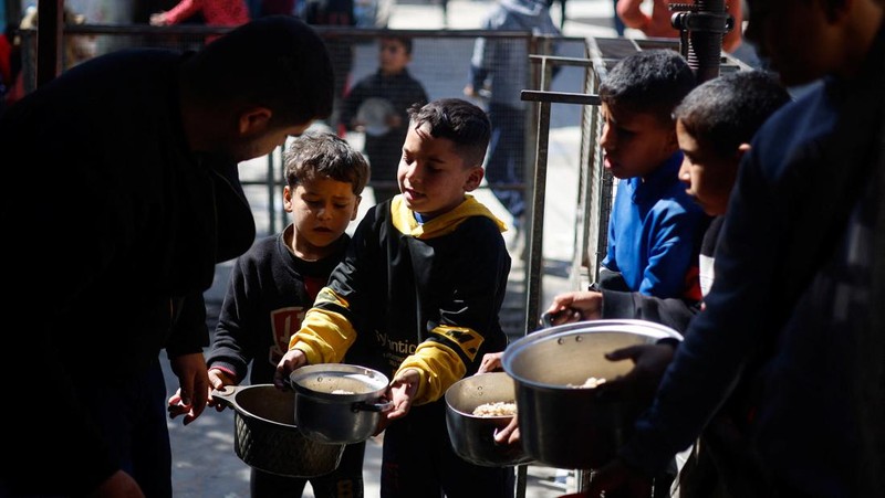 Anak-anak Palestina menunggu untuk menerima makanan yang dimasak oleh dapur amal di tengah kekurangan pasokan makanan, ketika konflik yang sedang berlangsung antara Israel dan kelompok Islam Palestina Hamas berlanjut, di Rafah, di selatan Jalur Gaza, 5 Maret 2024. (REUTERS/Mohammed Salem)