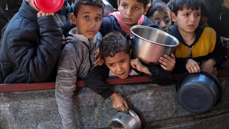 Anak-anak Palestina menunggu untuk menerima makanan yang dimasak oleh dapur amal di tengah kekurangan pasokan makanan, ketika konflik yang sedang berlangsung antara Israel dan kelompok Islam Palestina Hamas berlanjut, di Rafah, di selatan Jalur Gaza, 5 Maret 2024. (REUTERS/Mohammed Salem)