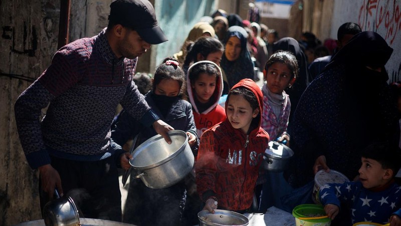 Anak-anak Palestina menunggu untuk menerima makanan yang dimasak oleh dapur amal di tengah kekurangan pasokan makanan, ketika konflik yang sedang berlangsung antara Israel dan kelompok Islam Palestina Hamas berlanjut, di Rafah, di selatan Jalur Gaza, 5 Maret 2024. (REUTERS/Mohammed Salem)