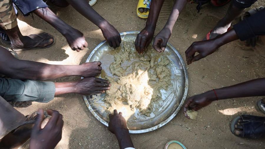 Pengungsi menyantap makanan di kamp pengungsi Adre Sudan di Adre, Chad, 8 November 2023. (REUTERS/El Tayeb Siddig/File Foto)