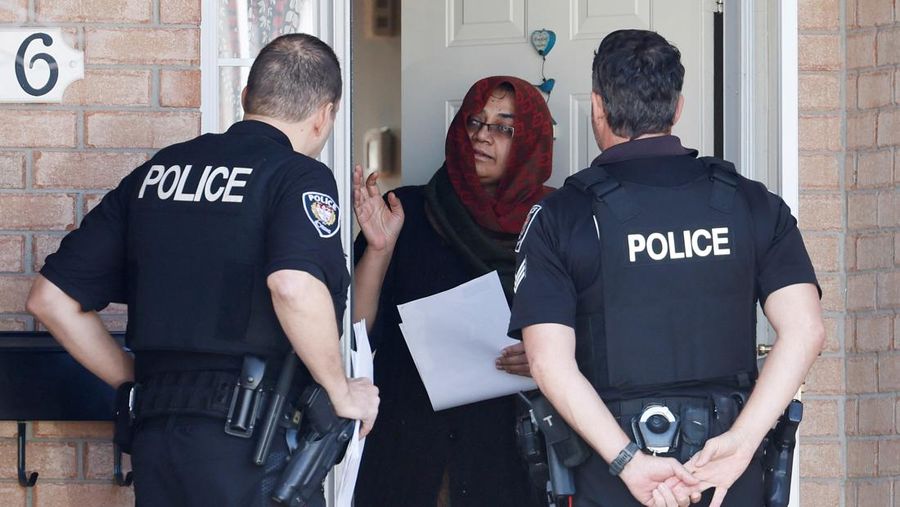 Ottawa Police Service officers surround a home after four children and two adults were found dead inside a neighbouring house in the Ottawa suburb of Barrhaven, Ontario, Canada March 7, 2024.  REUTERS/Blair Gable