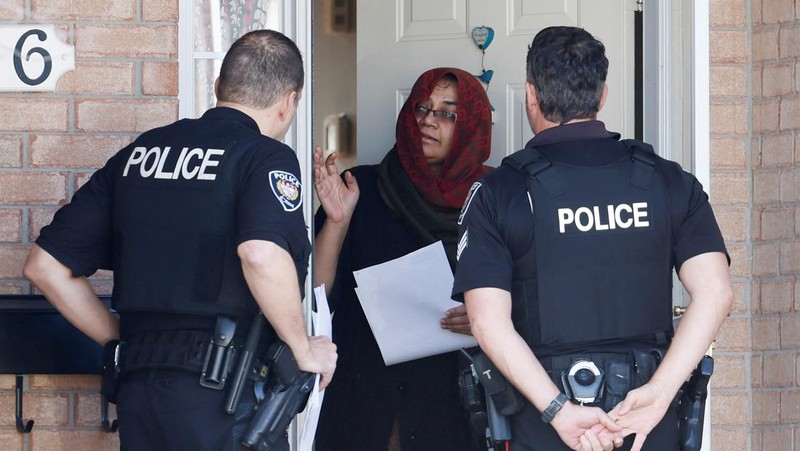 Ottawa Police Service officers surround a home after four children and two adults were found dead inside a neighbouring house in the Ottawa suburb of Barrhaven, Ontario, Canada March 7, 2024.  REUTERS/Blair Gable