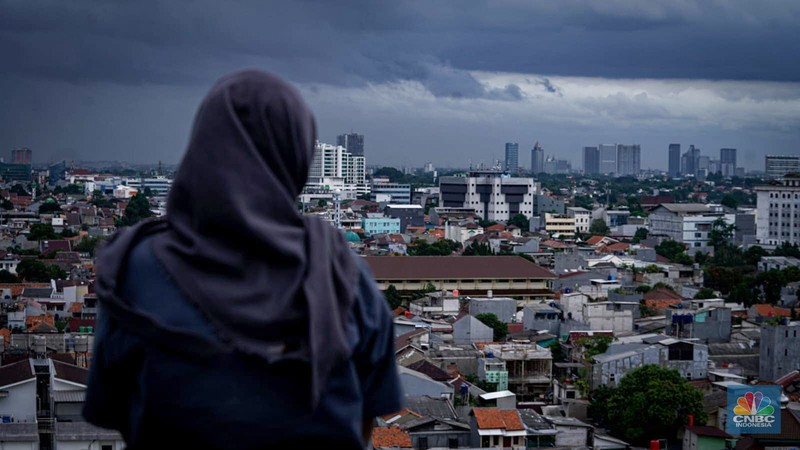 Seseorang melihat suasana langit tertutup awan gelap di Jakarta, Jumat (8/3/2024). (CNBC Indonesia/Tias Budiarto)