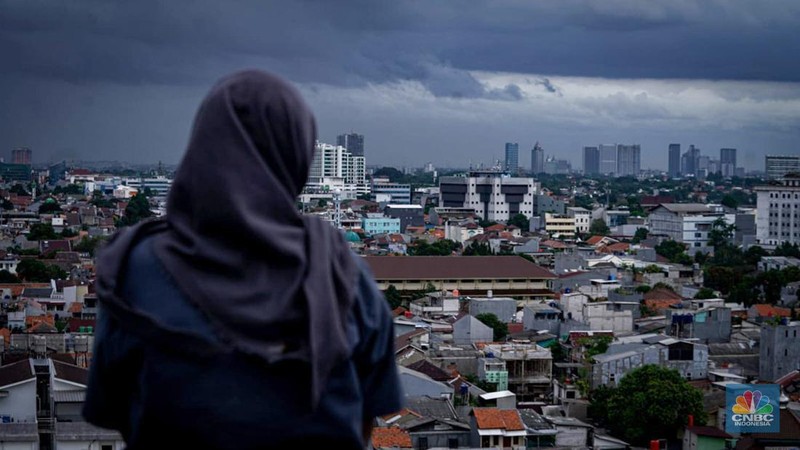 Seseorang melihat suasana langit tertutup awan gelap di Jakarta, Jumat (8/3/2024). (CNBC Indonesia/Tias Budiarto)