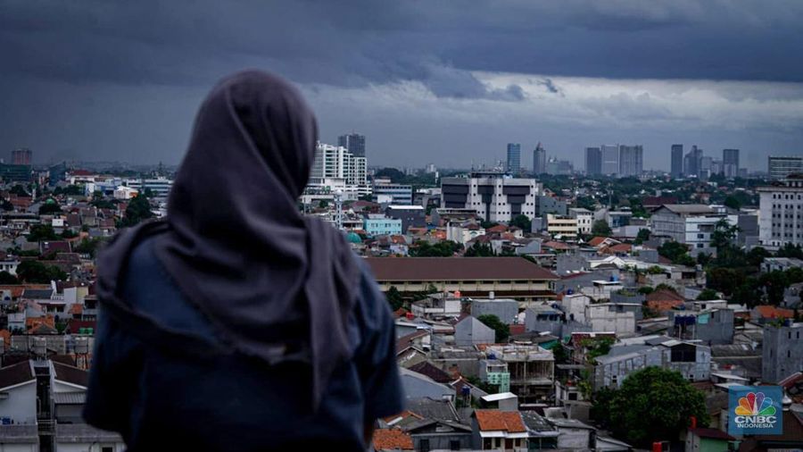 Seseorang melihat suasana langit tertutup awan gelap di Jakarta, Jumat (8/3/2024). (CNBC Indonesia/Tias Budiarto)