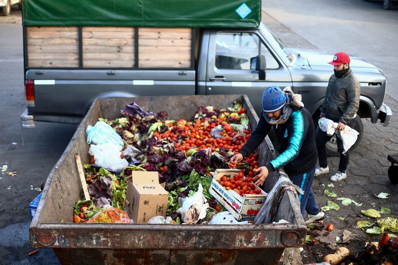 Perempuan mengumpulkan sayuran untuk dibawa pulang setelah dibuang oleh penjual di pasar di pinggiran Buenos Aires, Argentina, Rabu, 10 Januari 2024. (AP Photo/Natacha Pisarenko)