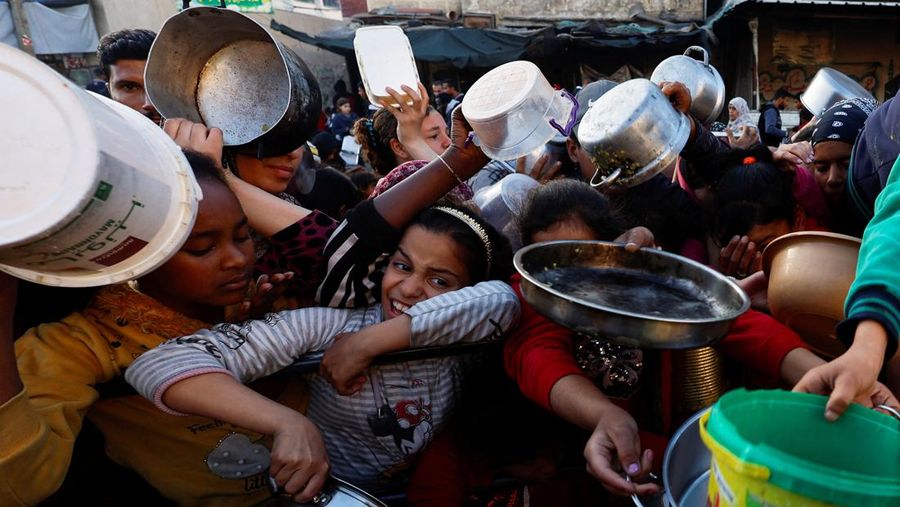 Warga Palestina menunggu untuk menerima makanan selama bulan suci Ramadhan, saat konflik antara Israel dan Hamas berlanjut, di Rafah, di selatan Jalur Gaza 13 Maret 2024. (REUTERS/Mohammed Salem)