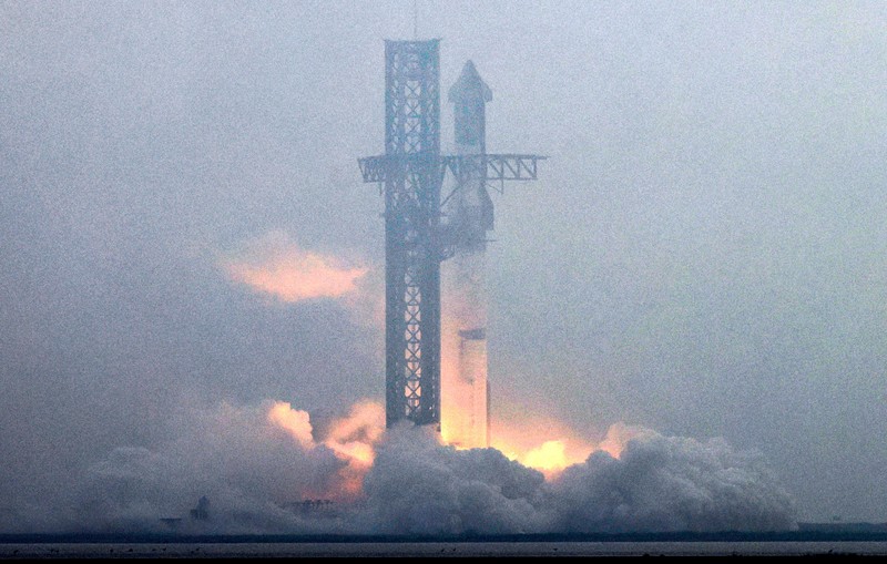 Para pekerja beristirahat sambil memindahkan bebatuan dan puing-puing dari area sekitar saat pesawat luar angkasa Starship generasi berikutnya milik SpaceX yang berada di atas roket Super Heavy. (REUTERS/Cheney Orr)