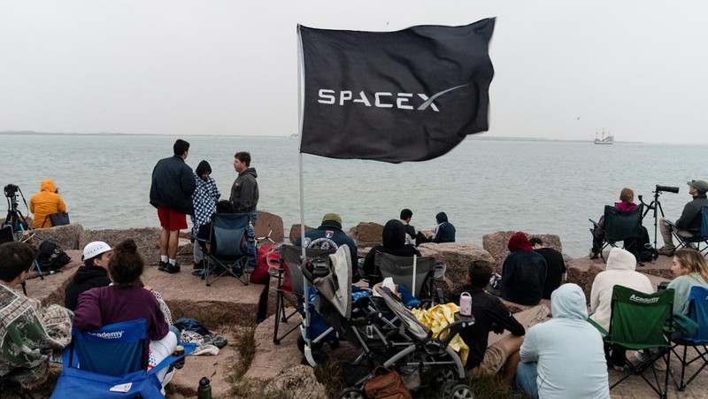 Para pekerja beristirahat sambil memindahkan bebatuan dan puing-puing dari area sekitar saat pesawat luar angkasa Starship generasi berikutnya milik SpaceX yang berada di atas roket Super Heavy. (REUTERS/Cheney Orr)