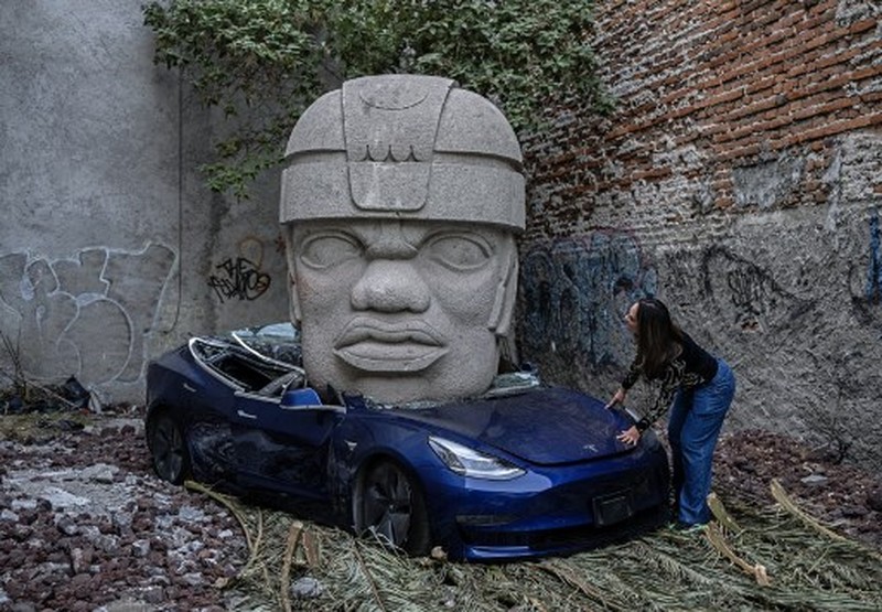 An artwork by artist Chavis Marmol, a Tesla 3 car crushed by a nine-ton Olmec-inspired head, is pictured in Mexico City on March 13, 2024. A 42-year-old sculptor, Marmol has never owned a car and travels by bicycle, but he had the luxury of unloading with cranes the nine-ton effigy on a blue Tesla 3, one of the electric models manufactured by US billionaire Elon Musk's company. (Photo by CARL DE SOUZA / AFP) / RESTRICTED TO EDITORIAL USE - MANDATORY MENTION OF THE ARTIST UPON PUBLICATION - TO ILLUSTRATE THE EVENT AS SPECIFIED IN THE CAPTION