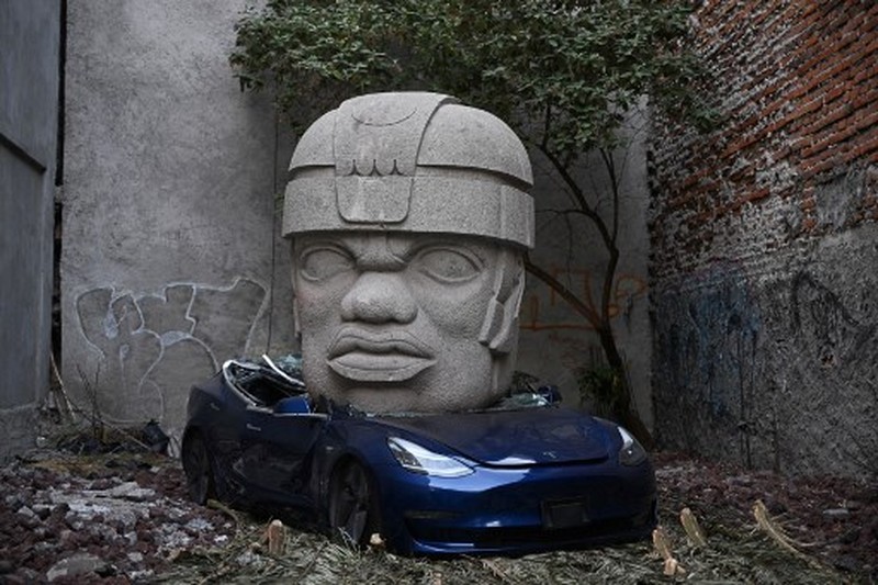 MEXICO-ART-CULTURE-OLMEC-TESLA An artwork by artist Chavis Marmol, a Tesla 3 car crushed by a nine-ton Olmec-inspired head, is pictured in Mexico City on March 13, 2024. A 42-year-old sculptor, Marmol has never owned a car and travels by bicycle, but he had the luxury of unloading with cranes the nine-ton effigy on a blue Tesla 3, one of the electric models manufactured by US billionaire Elon Musk's company. (Photo by CARL DE SOUZA / AFP) / RESTRICTED TO EDITORIAL USE - MANDATORY MENTION OF THE ARTIST UPON PUBLICATION - TO ILLUSTRATE THE EVENT AS SPECIFIED IN THE CAPTION