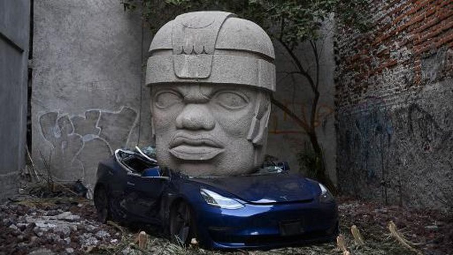 An artwork by artist Chavis Marmol, a Tesla 3 car crushed by a nine-ton Olmec-inspired head, is pictured in Mexico City on March 13, 2024. A 42-year-old sculptor, Marmol has never owned a car and travels by bicycle, but he had the luxury of unloading with cranes the nine-ton effigy on a blue Tesla 3, one of the electric models manufactured by US billionaire Elon Musk's company. (Photo by CARL DE SOUZA / AFP) / RESTRICTED TO EDITORIAL USE - MANDATORY MENTION OF THE ARTIST UPON PUBLICATION - TO ILLUSTRATE THE EVENT AS SPECIFIED IN THE CAPTION