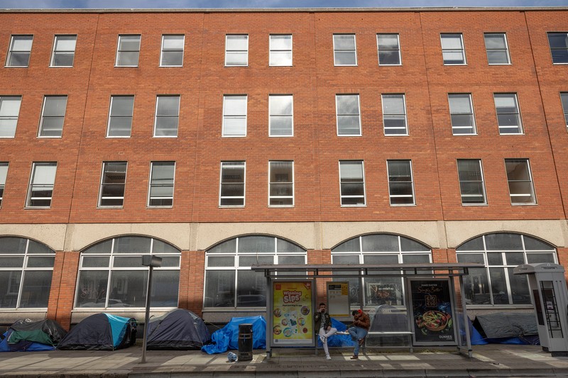 Newly arrived asylum seekers walks past tents belonging to homeless asylum seekers outside the International Protection Office (IPO), where hundreds in search of accommodation have been sleeping on the streets for several months with more arriving every day, in Dublin, Ireland, March 14, 2024. REUTERS/Clodagh Kilcoyne