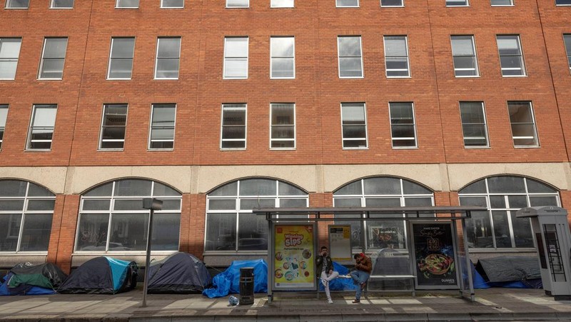 Newly arrived asylum seekers walks past tents belonging to homeless asylum seekers outside the International Protection Office (IPO), where hundreds in search of accommodation have been sleeping on the streets for several months with more arriving every day, in Dublin, Ireland, March 14, 2024. REUTERS/Clodagh Kilcoyne