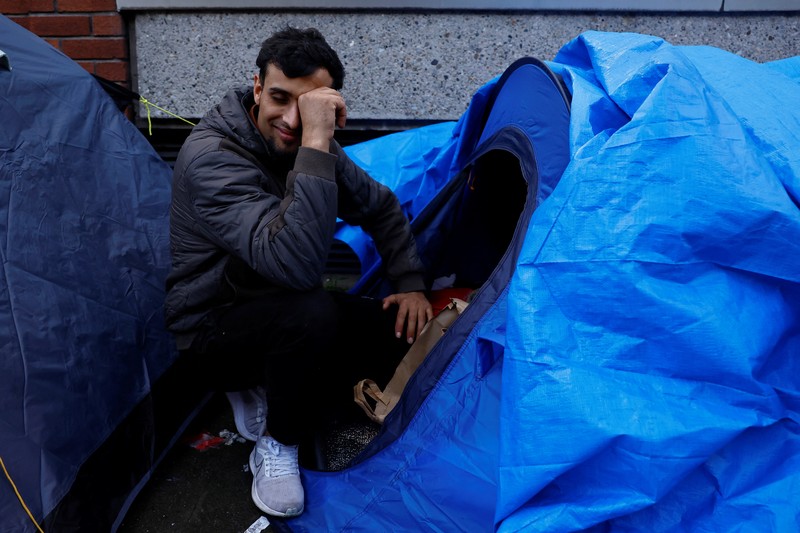 IRELAND-REFUGEES/ Newly arrived asylum seekers walks past tents belonging to homeless asylum seekers outside the International Protection Office (IPO), where hundreds in search of accommodation have been sleeping on the streets for several months with more arriving every day, in Dublin, Ireland, March 14, 2024. REUTERS/Clodagh Kilcoyne
