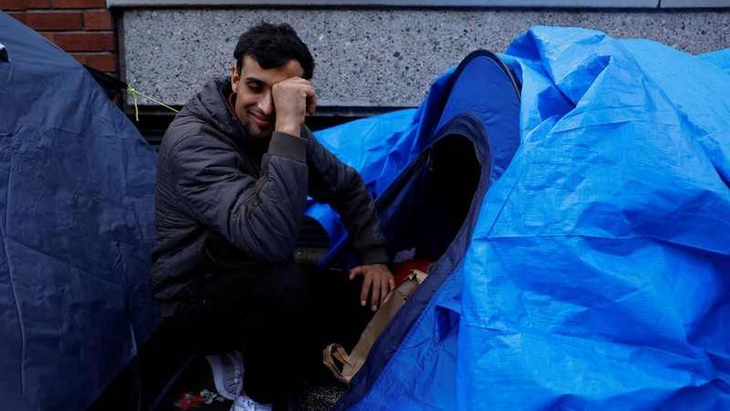 Newly arrived asylum seekers walks past tents belonging to homeless asylum seekers outside the International Protection Office (IPO), where hundreds in search of accommodation have been sleeping on the streets for several months with more arriving every day, in Dublin, Ireland, March 14, 2024. REUTERS/Clodagh Kilcoyne