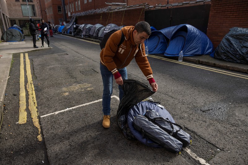 IRELAND-REFUGEES/ Newly arrived asylum seekers walks past tents belonging to homeless asylum seekers outside the International Protection Office (IPO), where hundreds in search of accommodation have been sleeping on the streets for several months with more arriving every day, in Dublin, Ireland, March 14, 2024. REUTERS/Clodagh Kilcoyne