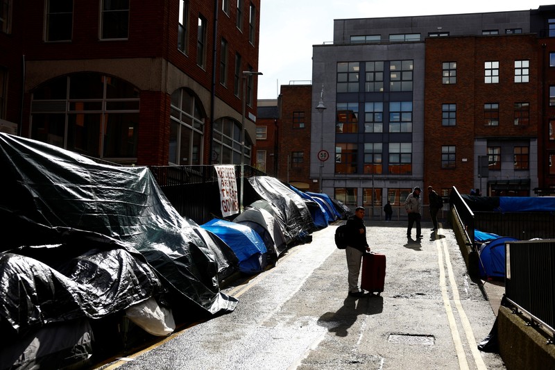 IRELAND-REFUGEES/ Newly arrived asylum seekers walks past tents belonging to homeless asylum seekers outside the International Protection Office (IPO), where hundreds in search of accommodation have been sleeping on the streets for several months with more arriving every day, in Dublin, Ireland, March 14, 2024. REUTERS/Clodagh Kilcoyne