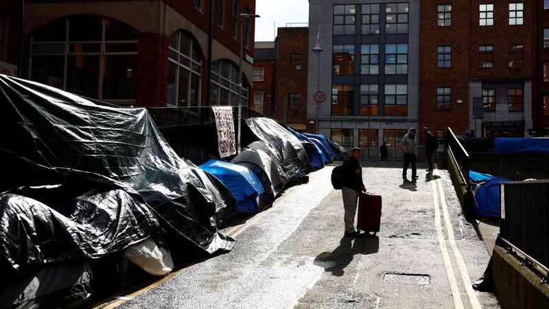 Newly arrived asylum seekers walks past tents belonging to homeless asylum seekers outside the International Protection Office (IPO), where hundreds in search of accommodation have been sleeping on the streets for several months with more arriving every day, in Dublin, Ireland, March 14, 2024. REUTERS/Clodagh Kilcoyne