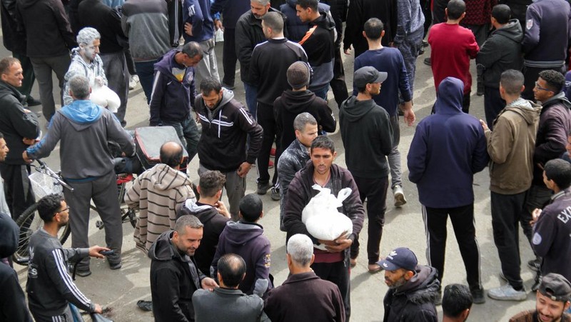 Warga Palestina berkumpul untuk menerima bantuan di luar gudang UNRWA saat warga Gaza menghadapi krisis kelaparan, di tengah konflik yang sedang berlangsung antara Israel dan Hamas, di Kota Gaza 18 Maret 2024. (REUTERS/Mahmoud Issa)
