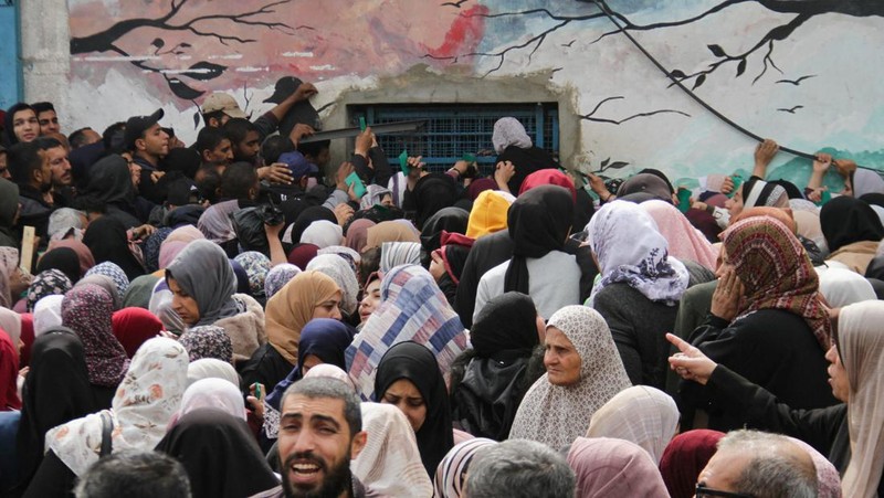 Warga Palestina berkumpul untuk menerima bantuan di luar gudang UNRWA saat warga Gaza menghadapi krisis kelaparan, di tengah konflik yang sedang berlangsung antara Israel dan Hamas, di Kota Gaza 18 Maret 2024. (REUTERS/Mahmoud Issa)