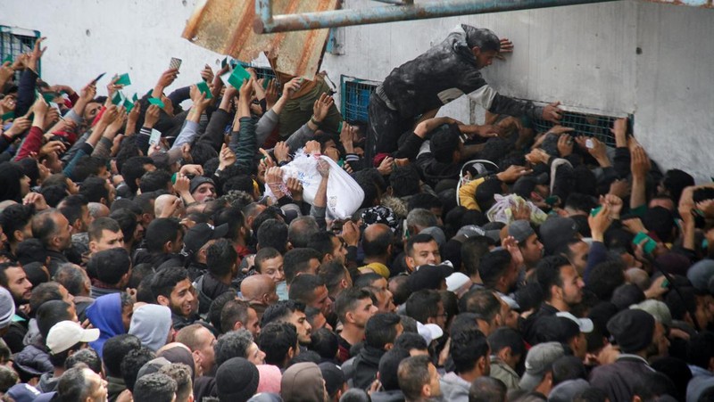 Warga Palestina berkumpul untuk menerima bantuan di luar gudang UNRWA saat warga Gaza menghadapi krisis kelaparan, di tengah konflik yang sedang berlangsung antara Israel dan Hamas, di Kota Gaza 18 Maret 2024. (REUTERS/Mahmoud Issa)