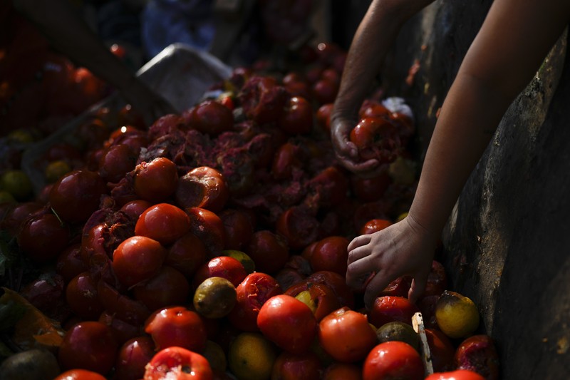 Perempuan mengumpulkan sayuran untuk dibawa pulang setelah dibuang oleh penjual di pasar di pinggiran Buenos Aires, Argentina, Rabu, 10 Januari 2024. (AP Photo/Natacha Pisarenko)