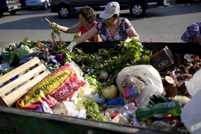 Perempuan mengumpulkan sayuran untuk dibawa pulang setelah dibuang oleh penjual di pasar di pinggiran Buenos Aires, Argentina, Rabu, 10 Januari 2024. (AP Photo/Natacha Pisarenko)
