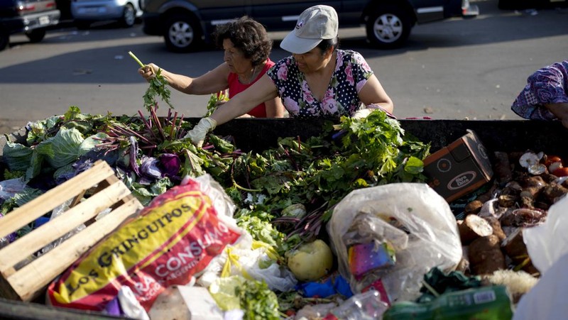 Perempuan mengumpulkan sayuran untuk dibawa pulang setelah dibuang oleh penjual di pasar di pinggiran Buenos Aires, Argentina, Rabu, 10 Januari 2024. (AP Photo/Natacha Pisarenko)