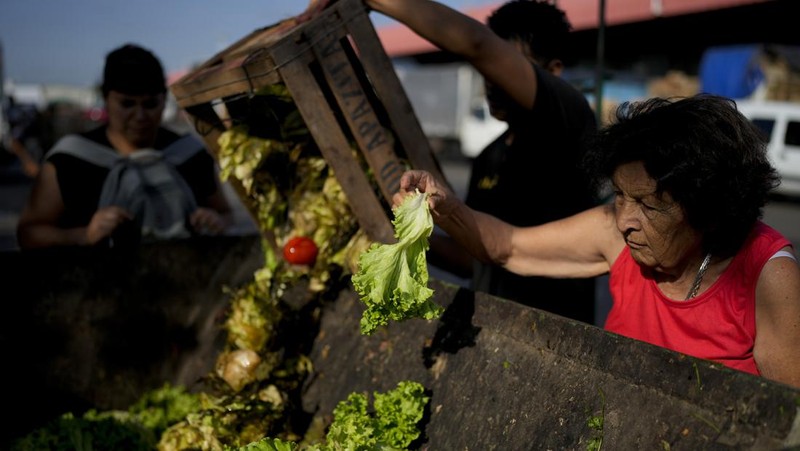 Perempuan mengumpulkan sayuran untuk dibawa pulang setelah dibuang oleh penjual di pasar di pinggiran Buenos Aires, Argentina, Rabu, 10 Januari 2024. (AP Photo/Natacha Pisarenko)
