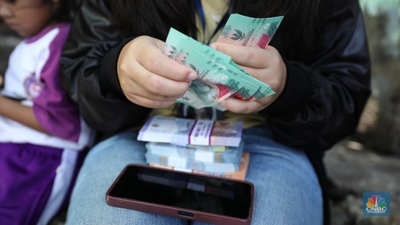 Warga melakukan penukaran uang pecahan di mobil kas keliling Bank Indonesia yang melayani penukaran uang pecahan di Pasar Slipi, Jakarta, Rabu (20/3/2024). (CNBC Indonesia/Tri Susilo)