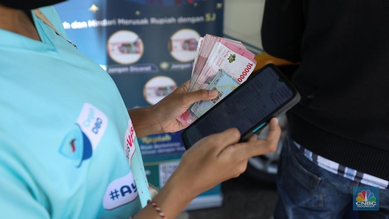 Warga melakukan penukaran uang pecahan di mobil kas keliling Bank Indonesia yang melayani penukaran uang pecahan di Pasar Slipi, Jakarta, Rabu (20/3/2024). (CNBC Indonesia/Tri Susilo)