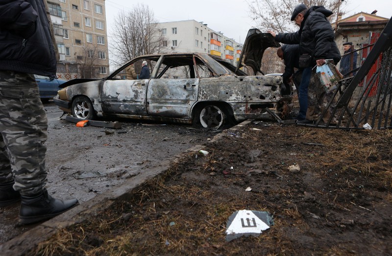 Warga memerika mobil yang rusak usai terkena serangan militer Ukraina di pemukiman Razumnoe, Belgorod, Rusia, Selasa (19/3/2024) waktu setempat. (REUTERS/Stringer)