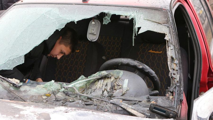 Warga memerika mobil yang rusak usai terkena serangan militer Ukraina di pemukiman Razumnoe, Belgorod, Rusia, Selasa (19/3/2024) waktu setempat. (REUTERS/Stringer)