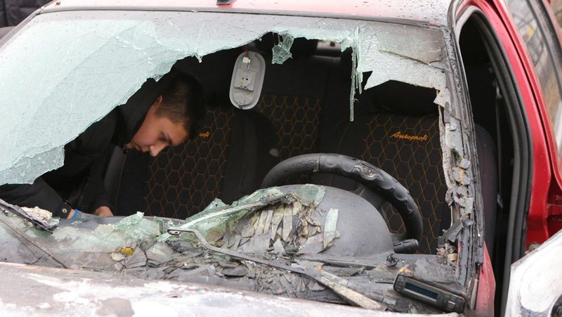 Warga memerika mobil yang rusak usai terkena serangan militer Ukraina di pemukiman Razumnoe, Belgorod, Rusia, Selasa (19/3/2024) waktu setempat. (REUTERS/Stringer)