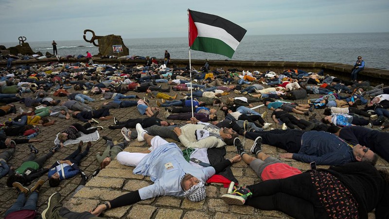Pro-Palestinian demonstrators lie on the ground as they protest against Israeli attacks on Gaza, in San Sebastian, northern Spain, on Sunday, March 17, 2024. (AP Photo/Alvaro Barrientos)