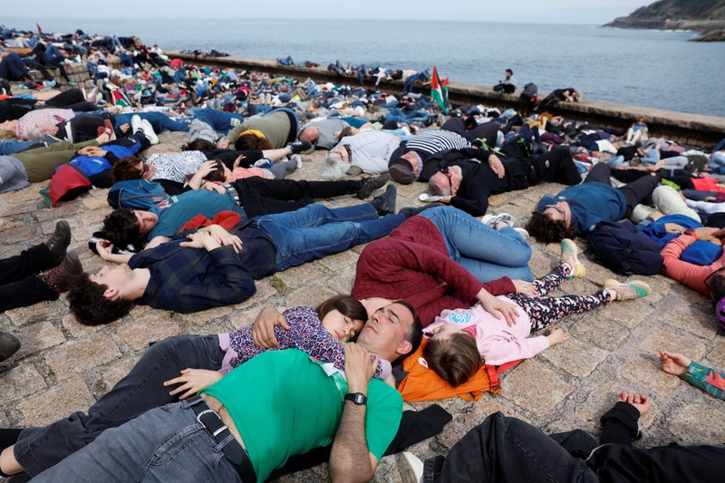 Pro-Palestinian demonstrators lie on the ground as they protest against Israeli attacks on Gaza, in San Sebastian, northern Spain, on Sunday, March 17, 2024. (AP Photo/Alvaro Barrientos)