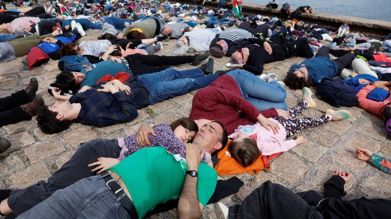 Pro-Palestinian demonstrators lie on the ground as they protest against Israeli attacks on Gaza, in San Sebastian, northern Spain, on Sunday, March 17, 2024. (AP Photo/Alvaro Barrientos)