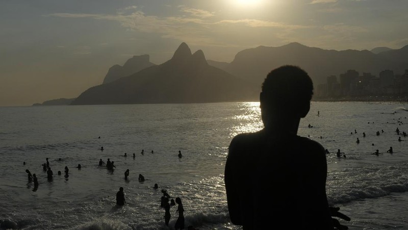 Orang-orang nongkrong di perairan dangkal pantai Arpoador di tengah gelombang panas, di Rio de Janeiro, Brasil, Rabu, 20 Maret 2024. (AP Photo/Silvia Izquierdo)