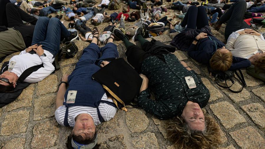 Pro-Palestinian demonstrators lie on the ground as they protest against Israeli attacks on Gaza, in San Sebastian, northern Spain, on Sunday, March 17, 2024. (AP Photo/Alvaro Barrientos)