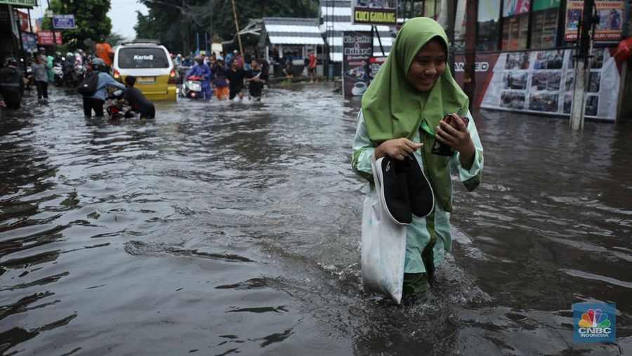 Warga melewati banjir yang merendam di kawasan Puribeta, Ciledug, Tangerang Selatan, Jumat (22/3/2024). (CNBC Indonesia/Tri Susilo)