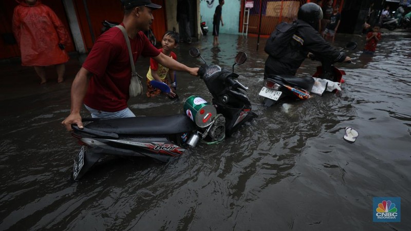 Warga melewati banjir yang merendam di kawasan Puribeta, Ciledug, Tangerang Selatan, Jumat (22/3/2024). (CNBC Indonesia/Tri Susilo)