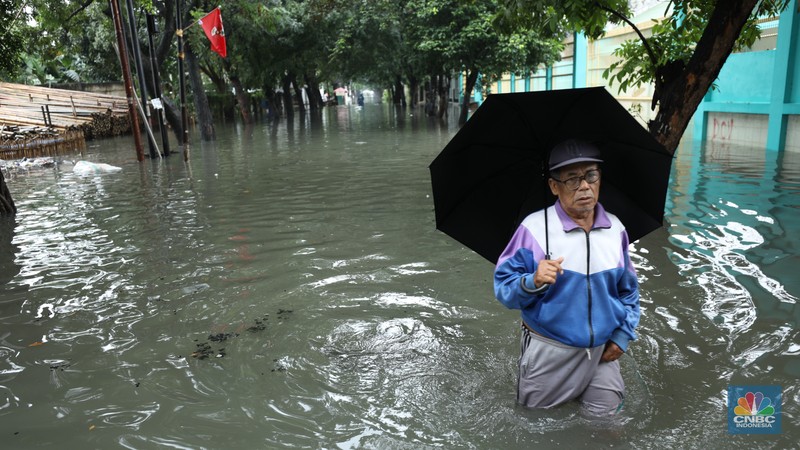 Warga melewati banjir yang merendam di kawasan Puribeta, Ciledug, Tangerang Selatan, Jumat (22/3/2024). (CNBC Indonesia/Tri Susilo)