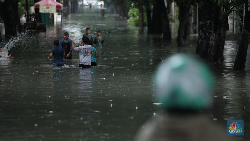Warga melewati banjir yang merendam di kawasan Puribeta, Ciledug, Tangerang Selatan, Jumat (22/3/2024). (CNBC Indonesia/Tri Susilo)