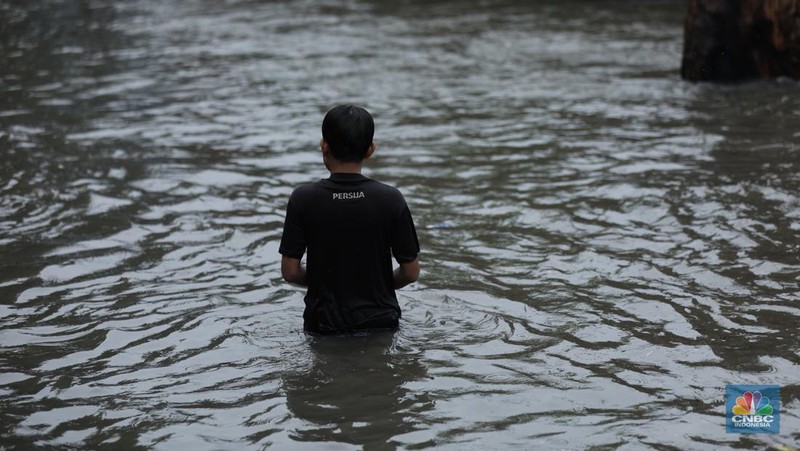 Warga melewati banjir yang merendam di kawasan Puribeta, Ciledug, Tangerang Selatan, Jumat (22/3/2024). (CNBC Indonesia/Tri Susilo)