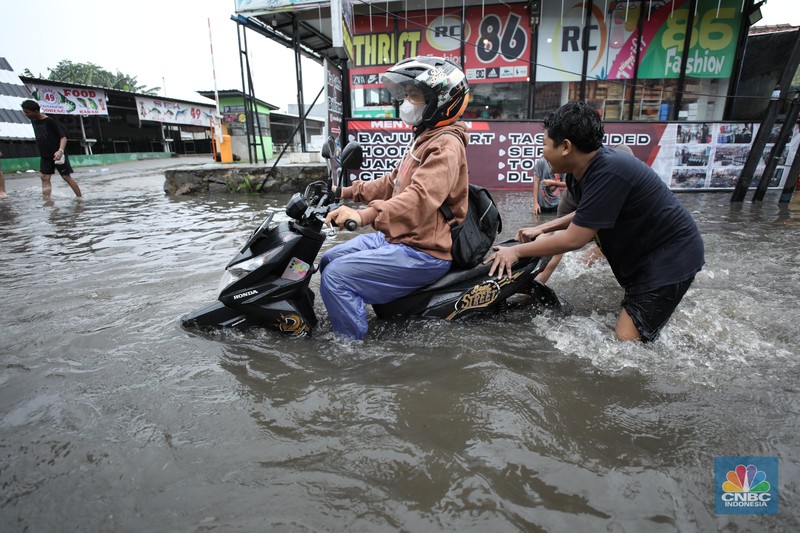 Warga melewati banjir yang merendam di kawasan Puribeta, Ciledug, Tangerang Selatan, Jumat (22/3/2024). (CNBC Indonesia/Tri Susilo)