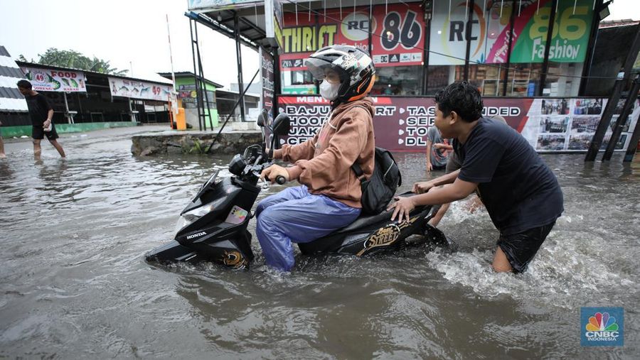 Warga melewati banjir yang merendam di kawasan Puribeta, Ciledug, Tangerang Selatan, Jumat (22/3/2024). (CNBC Indonesia/Tri Susilo)