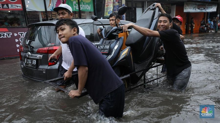 Warga melewati banjir yang merendam di kawasan Puribeta, Ciledug, Tangerang Selatan, Jumat (22/3/2024). (CNBC Indonesia/Tri Susilo)