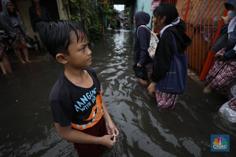 Warga melewati banjir yang merendam di kawasan Puribeta, Ciledug, Tangerang Selatan, Jumat (22/3/2024). (CNBC Indonesia/Tri Susilo)