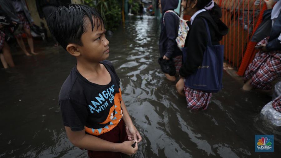 Warga melewati banjir yang merendam di kawasan Puribeta, Ciledug, Tangerang Selatan, Jumat (22/3/2024). (CNBC Indonesia/Tri Susilo)